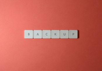 Free Close-up of keyboard keys spelling 'BACKUP' placed on a coral-colored surface. Stock Photo